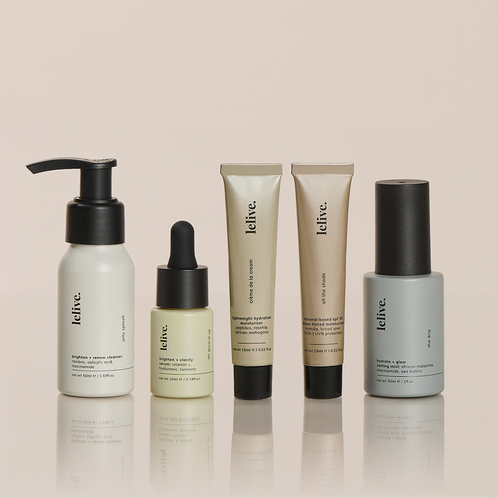 A collection of five mini skincare products from the brand Lelive, including a cleanser, brightening serum, moisturizer, tinted spf and a setting mist, each in travel-sized packaging.